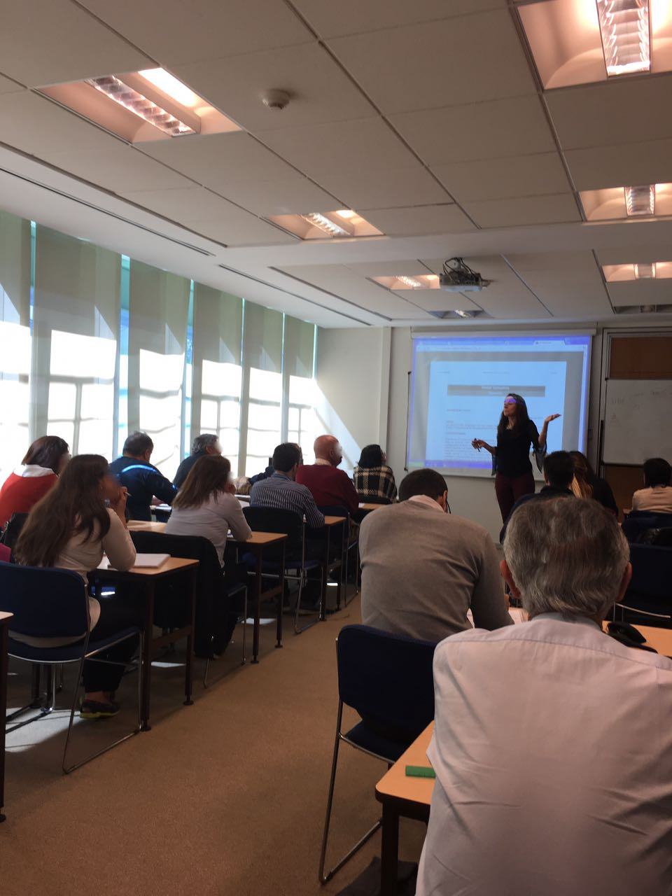 Contadora @SoyAndreaRubio, de Actualizarte, dictando una capacitación in-company presencial frente a un grupo de profesionales en una sala de reuniones.